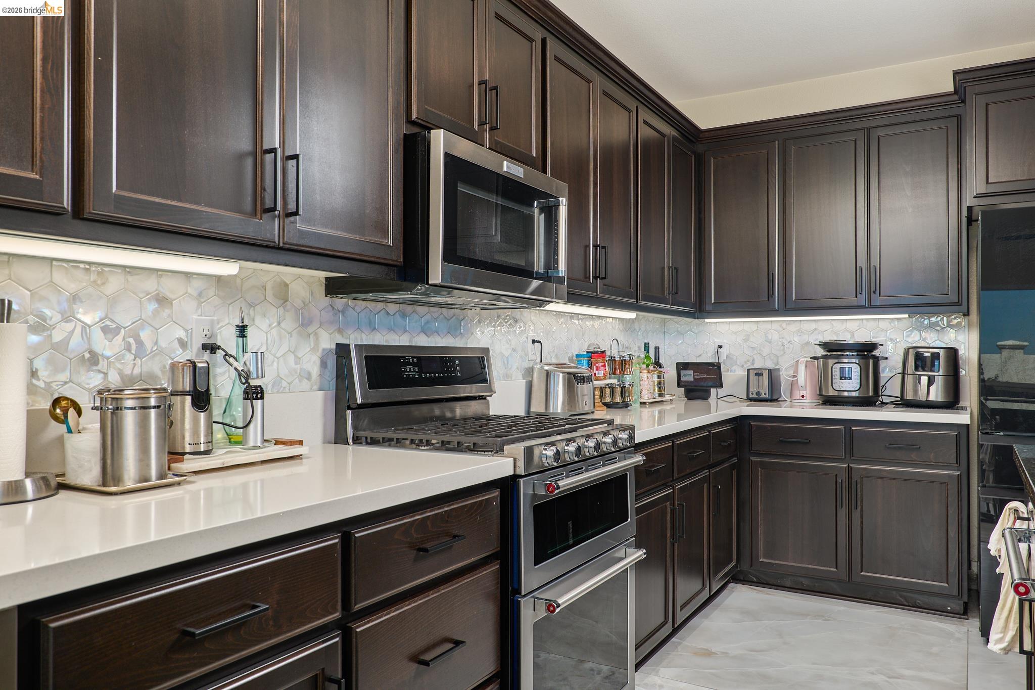 5532 Promontory Way Antioch, CA 94531 - Photo 7 of 45 Kitchen featuring dark wood finish cabinetry, stainless steel appliances, decorative backsplash, and light stone counters