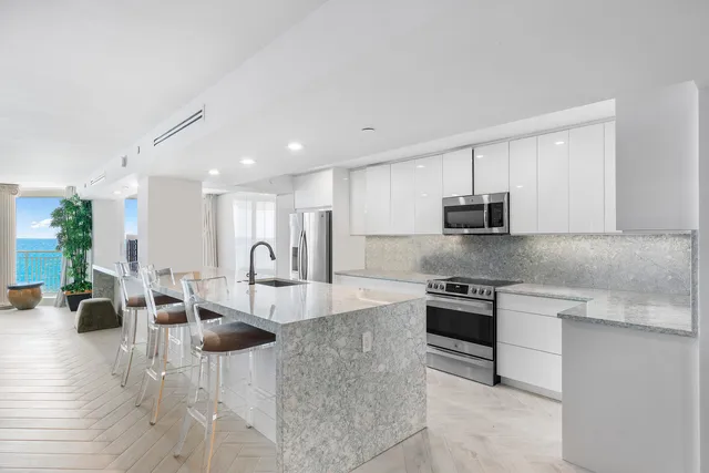 a large kitchen with stainless steel appliances granite countertop a sink dishwasher a stove and white cabinets with wooden floor