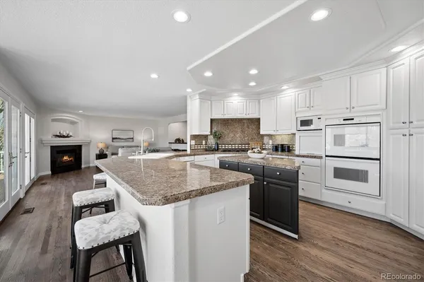 a large white kitchen with granite countertop a large window and white cabinets
