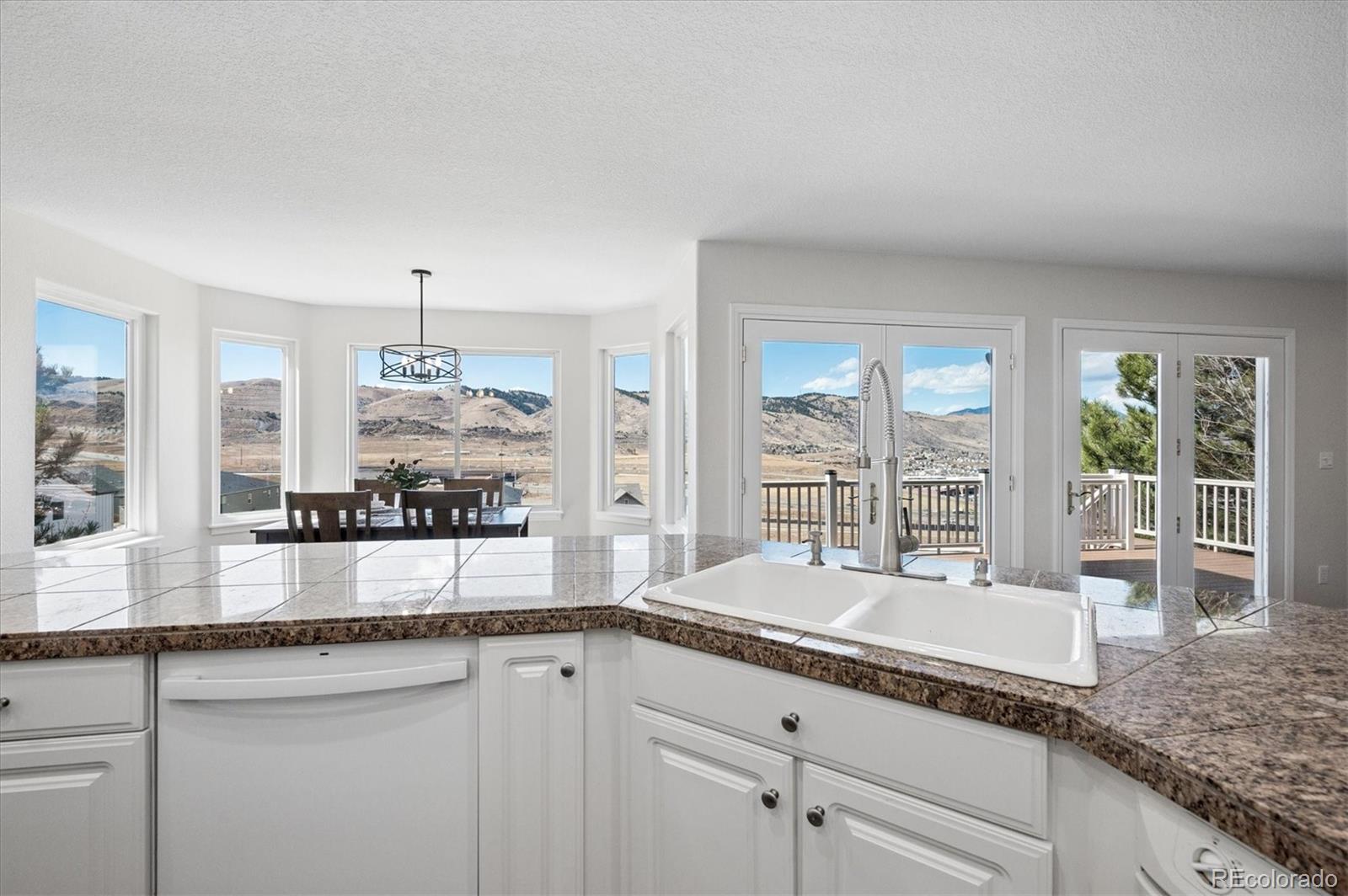 167 South Rogers Way Golden, CO 80401 - Photo 12 of 50 a large white kitchen with granite countertop a large window and white cabinets