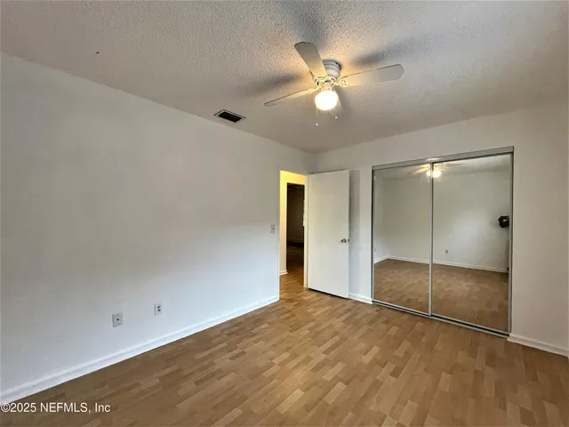an empty room with closet and a chandelier fan