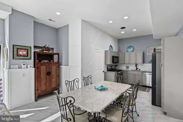 a living room with stainless steel appliances furniture a fireplace and a chandelier
