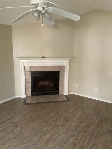 a view of an empty room with wooden floor fireplace and a window