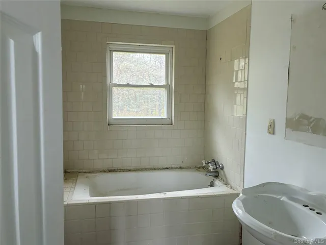 a bath tub sitting next to a white toilet and vanity