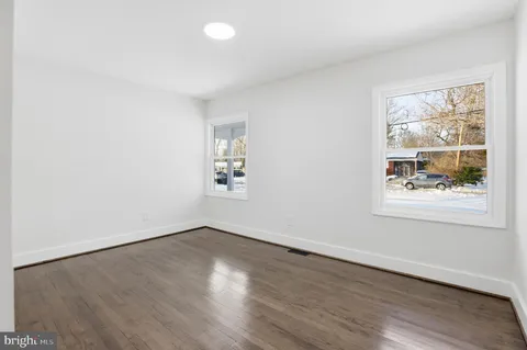 an empty room with wooden floor and window