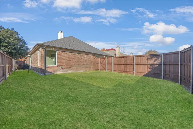 a view of a backyard with plants and large tree