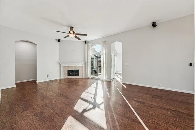 an empty room with wooden floor fireplace and windows