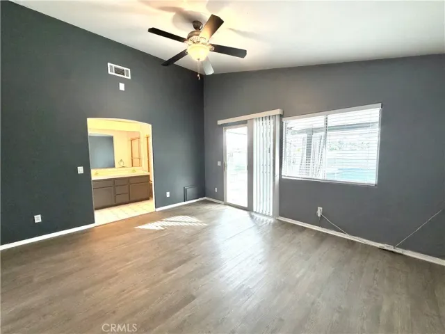 an empty room with wooden floor fan and windows