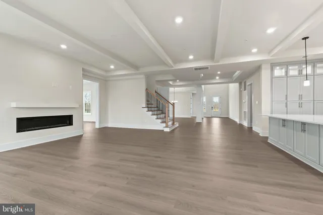 a view of an empty room with wooden floor and windows