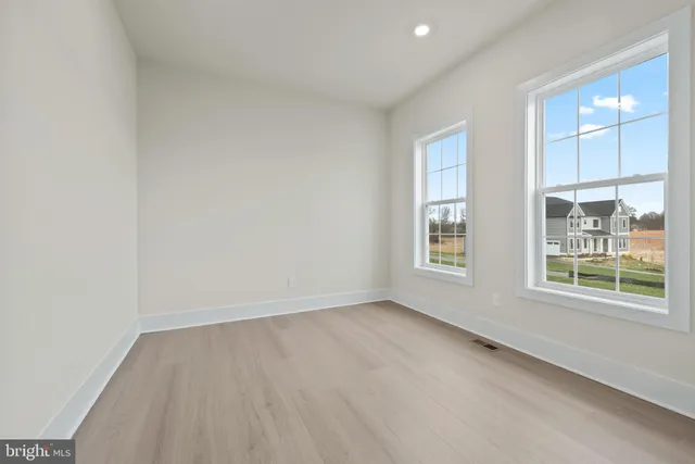 a view of an empty room with window and wooden floor