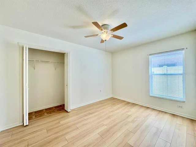 a view of empty room with wooden floor and fan