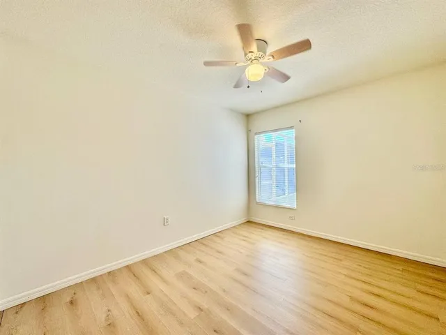 an empty room with a window and ceiling fan