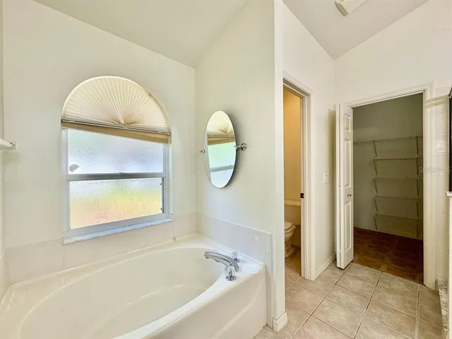 a bathroom with a tub a mirror and window