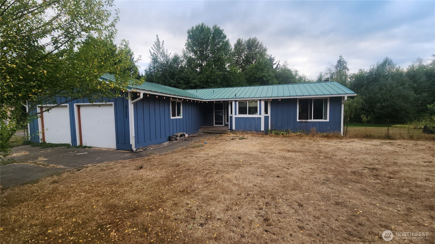 a front view of house with yard and trees in the background