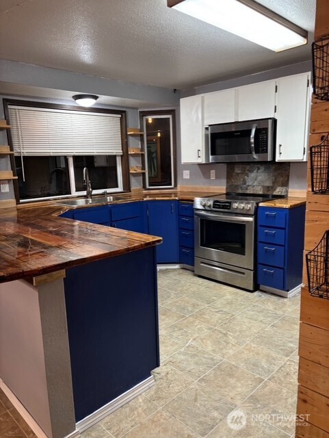 9735 Littlerock Road Southwest Olympia, WA 98512 - Photo 3 of 30 a kitchen with stainless steel appliances granite countertop a stove a sink and a microwave