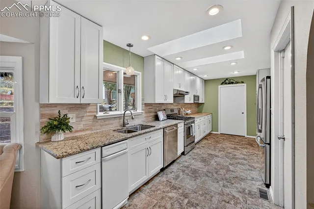 a kitchen with granite countertop a sink stainless steel appliances and cabinets