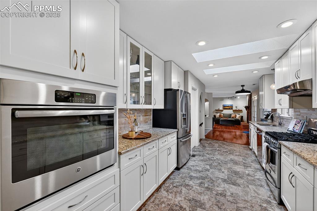3102 Brenner Place Colorado Springs, CO 80917 - Photo 3 of 38 a kitchen with stainless steel appliances kitchen island granite countertop a stove a sink and a refrigerator