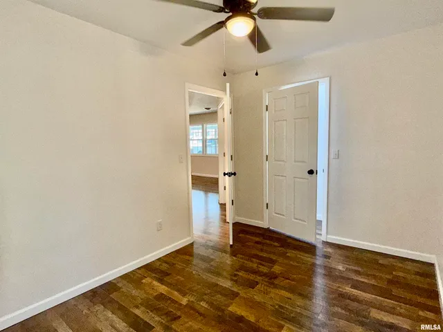 an empty room with wooden floor and a ceiling fan