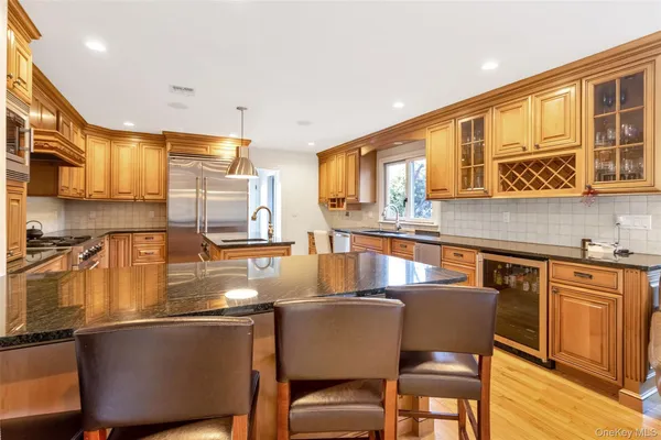 a kitchen with stainless steel appliances granite countertop a table chairs in it and wooden floors