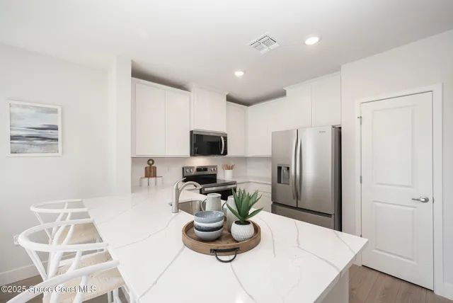 a kitchen with stainless steel appliances kitchen island granite countertop a refrigerator a stove a microwave and a refrigerator