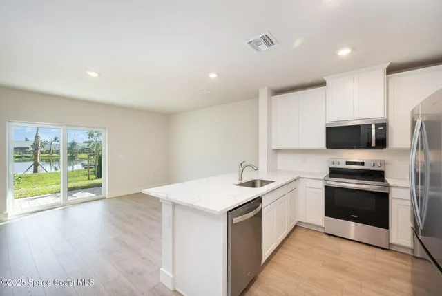 a large kitchen with stainless steel appliances granite countertop a stove a sink and a microwave