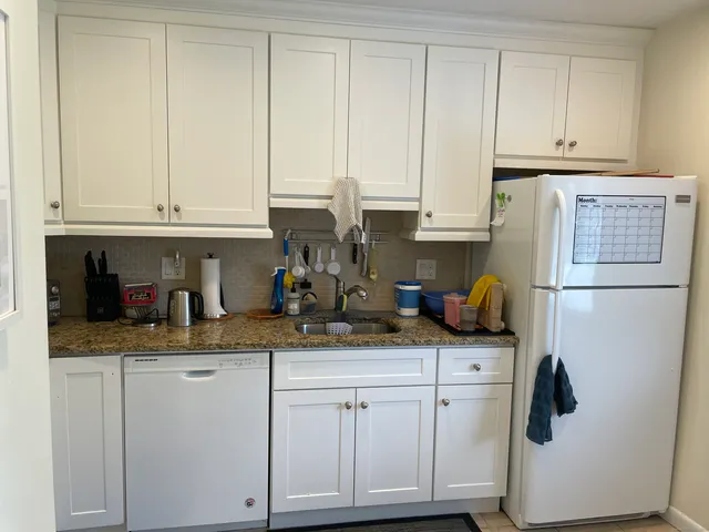 a kitchen with granite countertop white cabinets and refrigerator