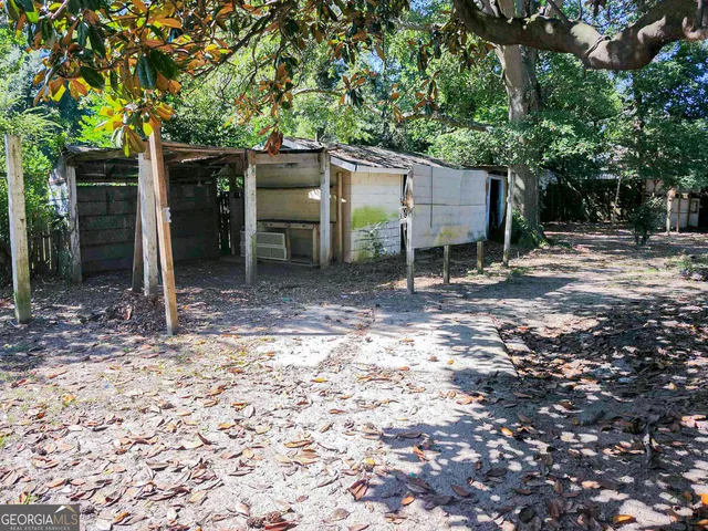 a view of a barn in the backyard with large tree and wooden fence