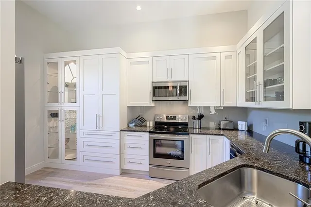 a kitchen with stainless steel appliances granite countertop a stove a sink and a microwave