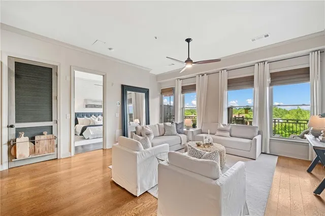a living room with furniture large window and wooden floor