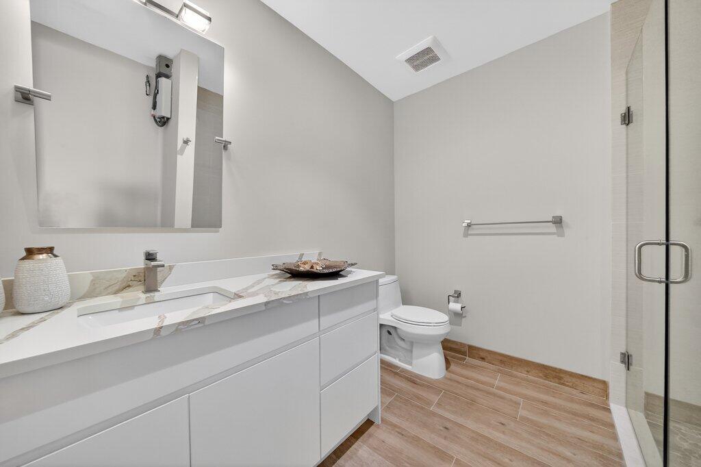 41 Southwest Seminole Street, Unit 304 Stuart, FL 34994 - Photo 6 of 29 a bathroom with a granite countertop toilet sink and a mirror