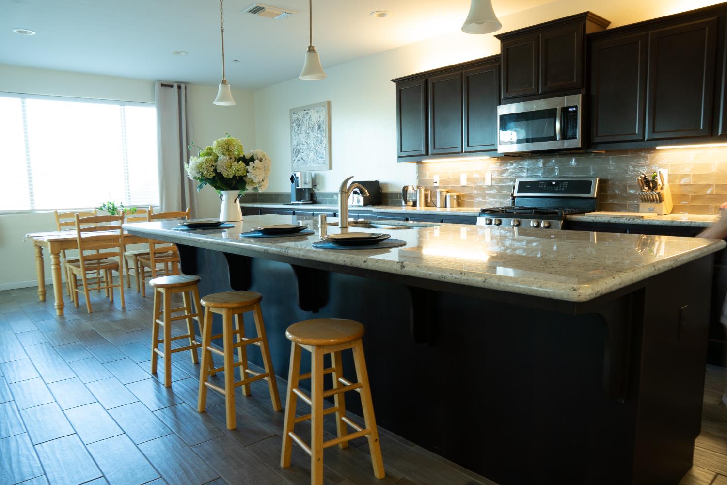 470 Daphne Lane Lemoore, CA 93245 - Photo 22 of 86 a kitchen with stainless steel appliances granite countertop a sink wooden cabinets dining table and chairs