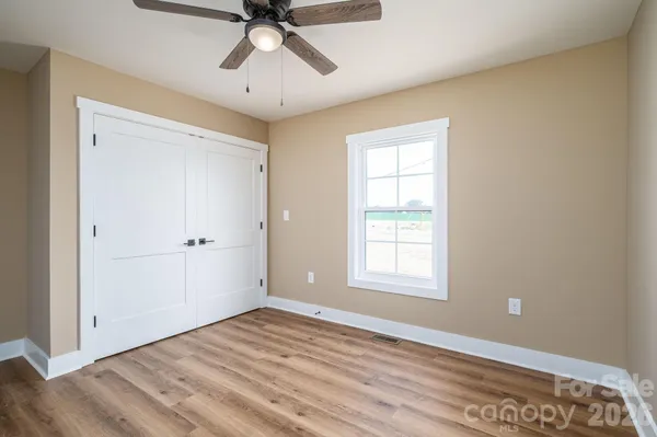 a view of empty room with wooden floor and fan