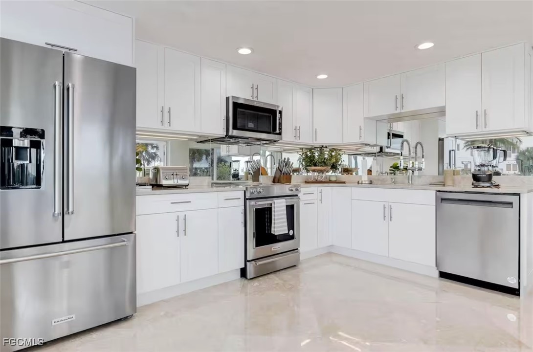 2740 North Beach Road, Unit A & B Englewood, FL 34223 - Photo 14 of 43 a kitchen with white cabinets and stainless steel appliances