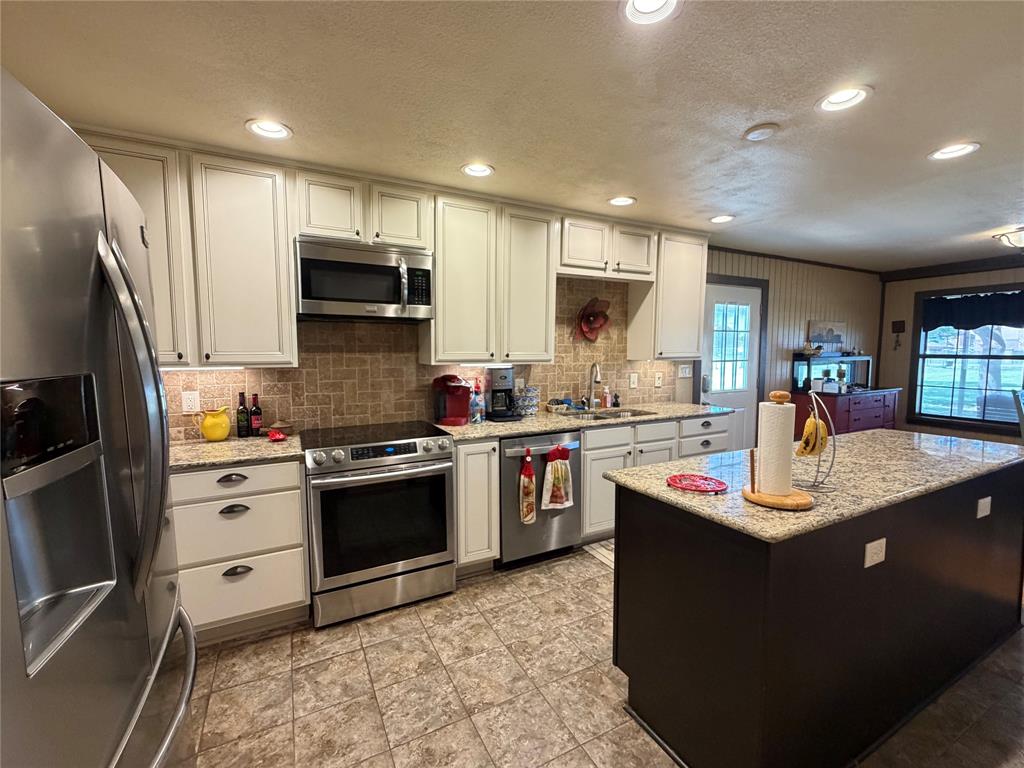 330 South Goode Road Wilmer, TX 75172 - Photo 16 of 38 a kitchen with kitchen island granite countertop a sink appliances and cabinets