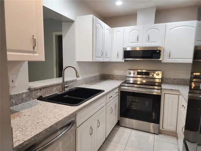 a kitchen with stainless steel appliances granite countertop a stove a sink and a microwave