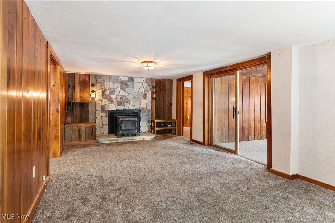 5070 Russell Road Andover, OH 44003 - Photo 22 of 25 Unfurnished living room with a wood stove, wood walls, and carpet