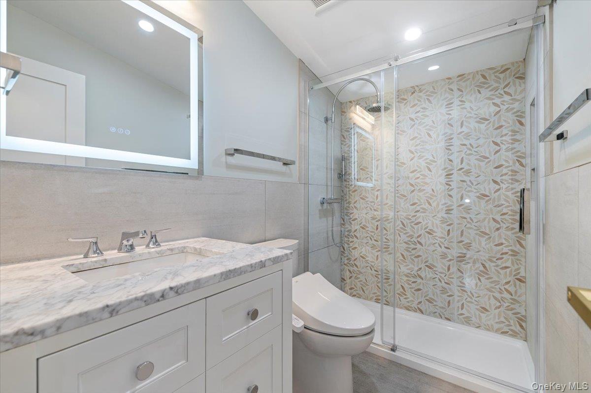 168 Martens Avenue Valley Stream, NY 11580 - Photo 15 of 26 Bathroom with tile walls, vanity, a shower stall, and recessed lighting