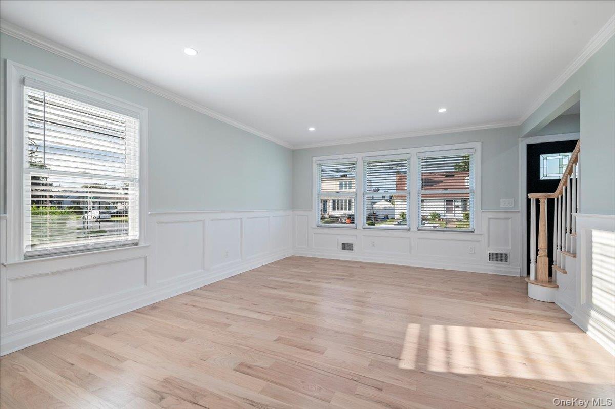 168 Martens Avenue Valley Stream, NY 11580 - Photo 5 of 26 Unfurnished room featuring healthy amount of natural light, light wood-style floors, ornamental molding, stairs, and a decorative wall