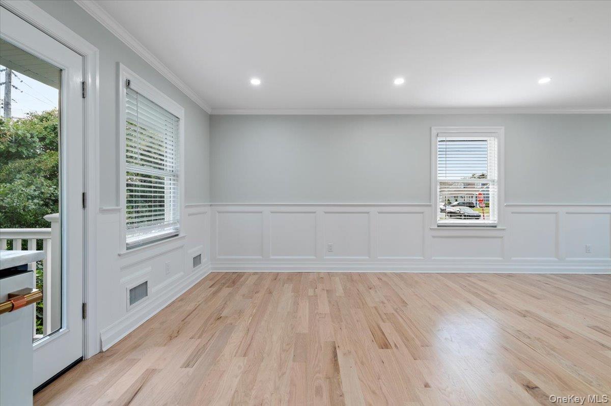 168 Martens Avenue Valley Stream, NY 11580 - Photo 8 of 26 Unfurnished room with crown molding, light wood finished floors, recessed lighting, a decorative wall, and a wainscoted wall