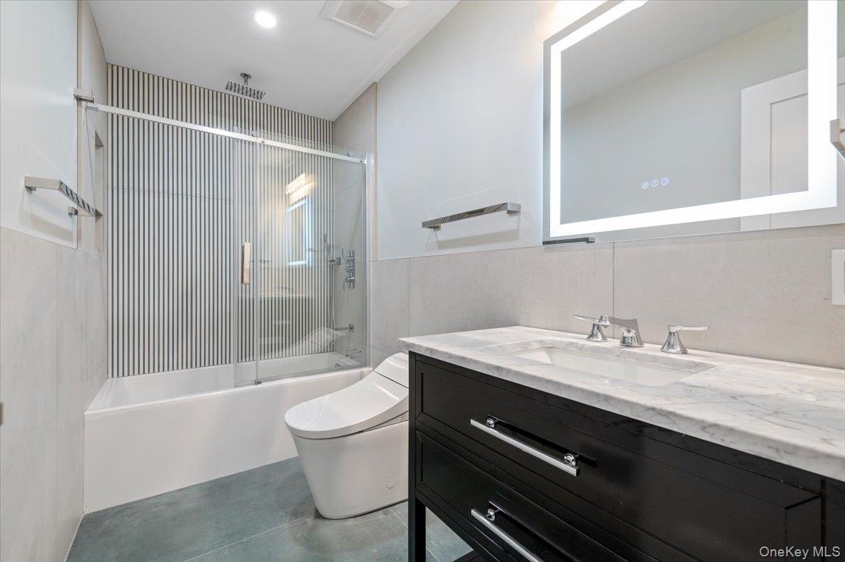 168 Martens Avenue Valley Stream, NY 11580 - Photo 10 of 26 Full bath with a combined bath / shower with rainfall shower, vanity, and wainscoting