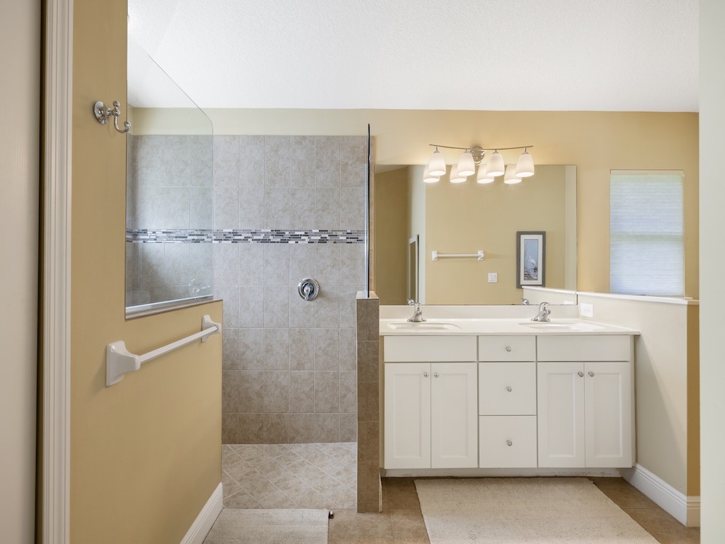 605 Monarch Way Sebastian, FL 32958 - Photo 17 of 36 a bathroom with a double vanity sink a mirror and a shower