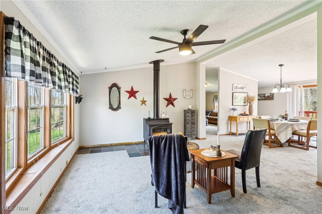 8307 Slagle Road Windham, OH 44288 - Photo 14 of 39 Dining space featuring a wood stove, carpet floors, a textured ceiling, lofted ceiling, and ceiling fan with notable chandelier