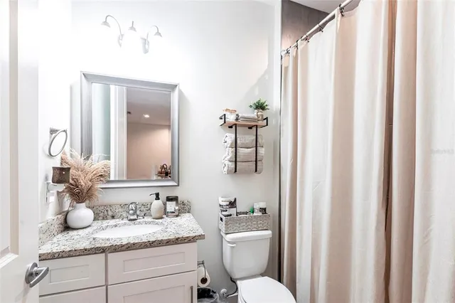 a bathroom with a granite countertop sink vanity mirror and toilet
