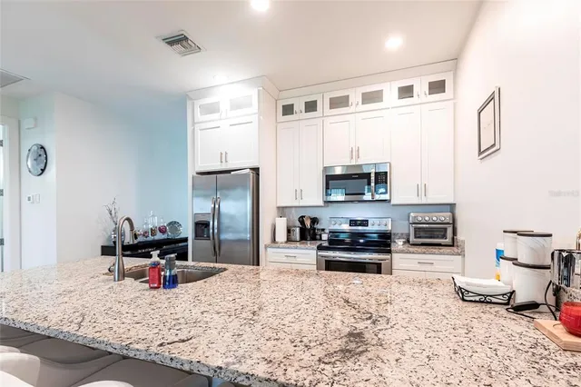 a kitchen with stainless steel appliances kitchen island granite countertop a stove refrigerator and sink