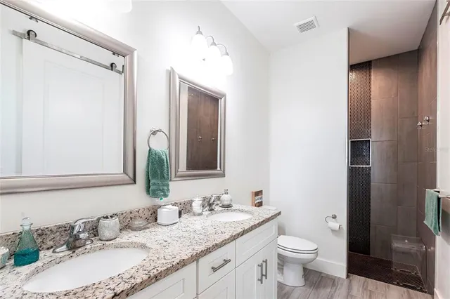 a bathroom with a granite countertop sink toilet and shower