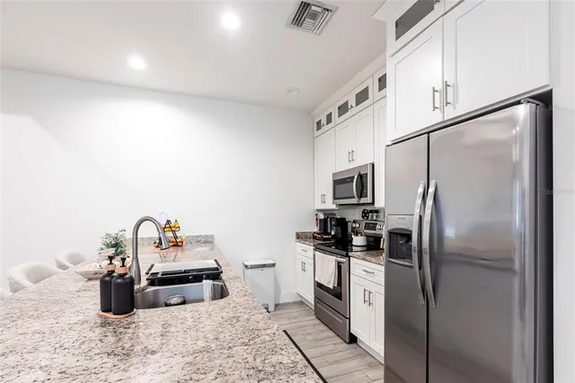 a kitchen with stainless steel appliances granite countertop a refrigerator a stove a sink and a microwave