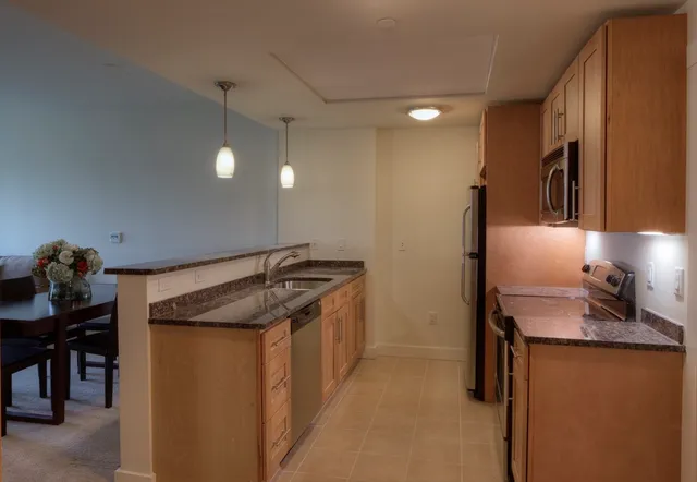 a kitchen with stainless steel appliances granite countertop a sink and a refrigerator