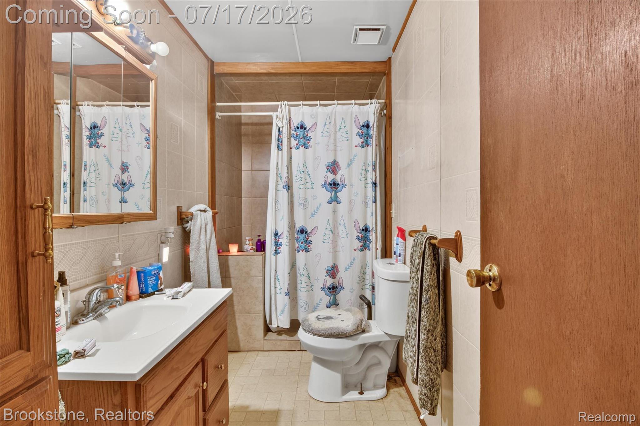 22709 Pleasant Valley Road Hillman, MI 49746 - Photo 17 of 42 Bathroom featuring a wood-finish vanity with an integrated sink, a mirrored medicine cabinet, a tiled shower/tub combination, and tiled walls