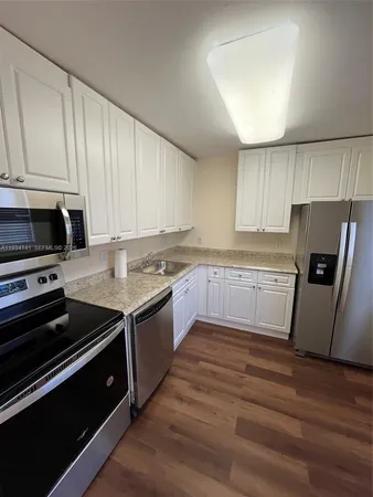 a kitchen with granite countertop a refrigerator stove top oven and sink