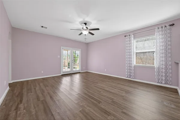 a view of an empty room with a window and wooden floor